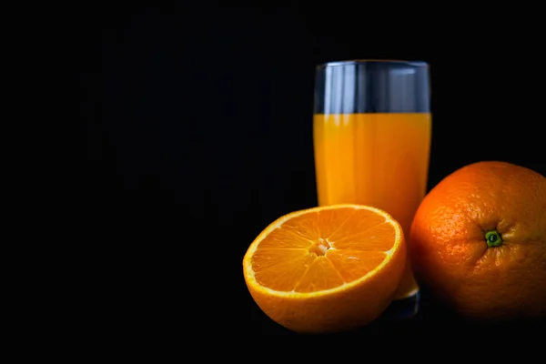 Orangenfrüchte und Saft isoliert auf schwarzem Hintergrund. — Stockfoto