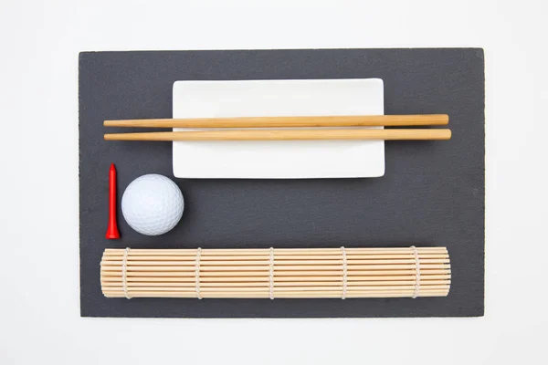 Piatto rettangolare in ardesia con bacchette per sushi e pallina da golf . — Foto Stock