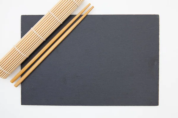 Rektangulär skifferplatta med ätpinnar, bambumatta för sushi o — Stockfoto
