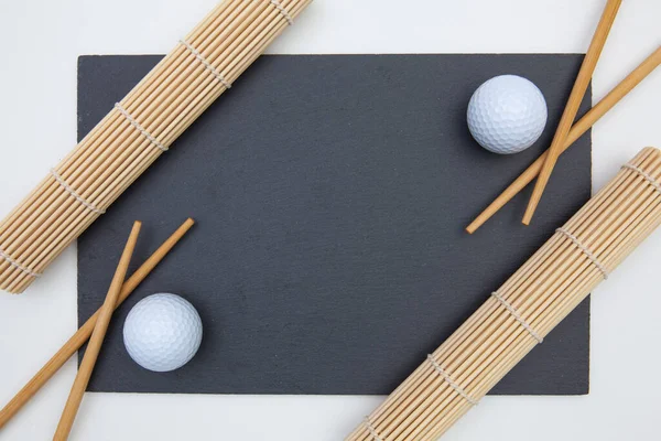 Placa rectangular de pizarra con palillos para sushi y pelota de golf . —  Fotos de Stock