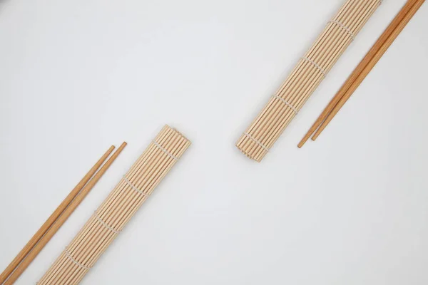 Estera de bambú con palillos para sushi en la mesa blanca . —  Fotos de Stock