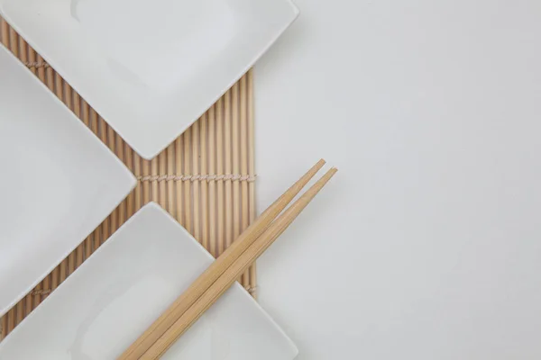 Bovenaanzicht van witte lege sushi platen met bamboe eetstokjes. — Stockfoto