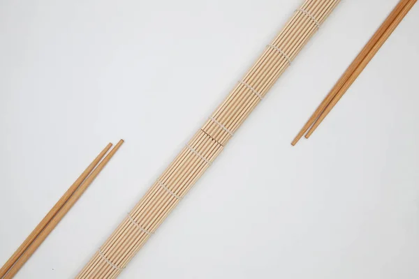 Στρώμα μπαμπού με ξυλάκια για σούσι στο λευκό τραπέζι. — Φωτογραφία Αρχείου
