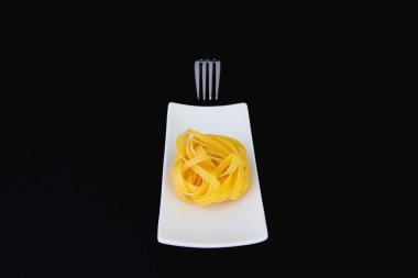 Beyaz tabakta paslanmaz çatal ve tagliatelle makarna. Diyet öğle yemeği.