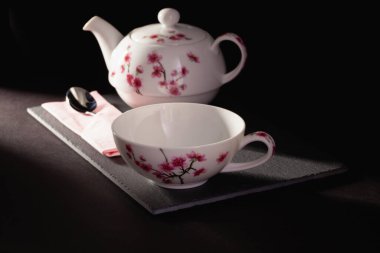 Bir fincan çay ve çaydanlık karanlık odadaki tabakta..