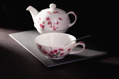 Bir fincan çay ve çaydanlık karanlık odadaki tabakta..