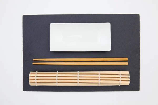 矩形石板与筷子 陶瓷板 竹子垫寿司在白桌上 食物设计 — 图库照片
