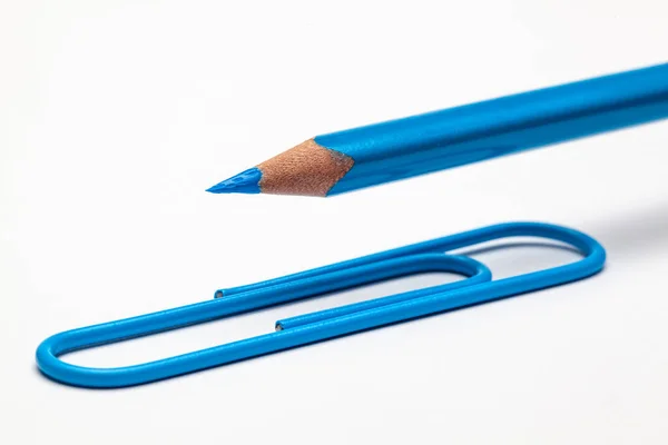 白いオフィステーブルの上に青い色の鉛筆と紙クリップを持ち上げる — ストック写真