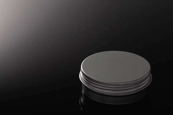 Silver metal containers for cosmetics isolated on the black glass desk.