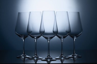 Mavi, temiz bir arka planda boş şarap kadehleri. Şeffaf şarap kadehleri boş.