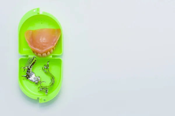 Dental prosthesis and skeletal pieces over a green box — Stock Photo, Image