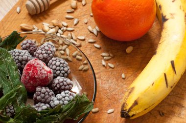 muz, portakal, dondurulmuş çilek böğürtlen ve tohum canlı smoothie maddeler arka planda