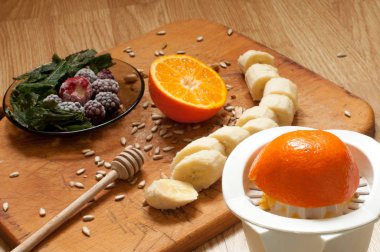 Yemek, el portakal suyu, muz, dondurulmuş çilek böğürtlen ve tohum canlı smoothie maddeler ve blender, meyva suyu sıkacağı, Lale arka plan üzerinde sıkar