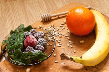 muz, portakal, dondurulmuş çilek böğürtlen ve tohum canlı smoothie maddeler arka planda