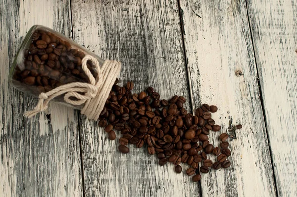 Granos de café dispersos en un frasco en madera — Foto de Stock