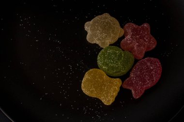 Siyah plaka arka plan üzerinde renkli jöle şekerler.