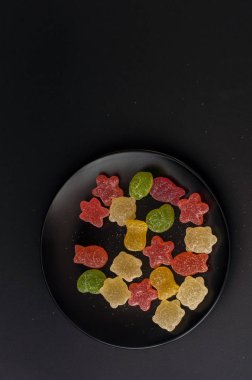 Siyah plaka arka plan üzerinde renkli jöle şekerler.