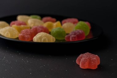 Siyah plaka arka plan üzerinde renkli jöle şekerler.