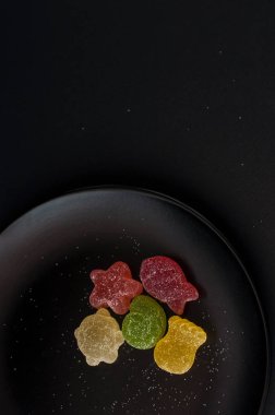 Siyah plaka arka plan üzerinde renkli jöle şekerler.