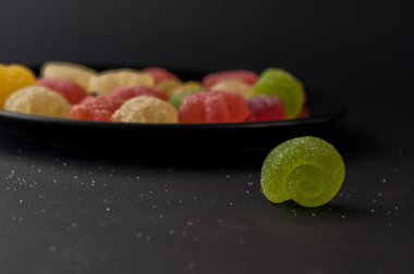 Siyah plaka arka plan üzerinde renkli jöle şekerler.