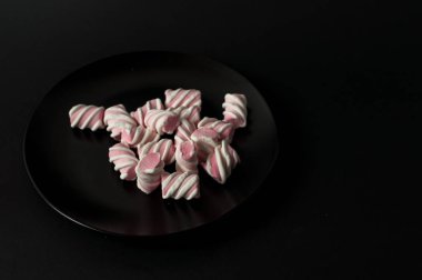 Marshmallow boşaltmak siyah zemin üzerine. Düz yatıyordu veya en iyi görünümü. Arka plan veya doku renkli mini lokum gibiydi.