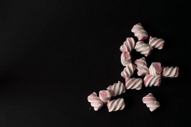 Marshmallow boşaltmak siyah zemin üzerine. Düz yatıyordu veya en iyi görünümü. Arka plan veya doku renkli mini lokum gibiydi.