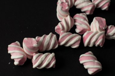 Marshmallow boşaltmak siyah zemin üzerine. Düz yatıyordu veya en iyi görünümü. Arka plan veya doku renkli mini lokum gibiydi.