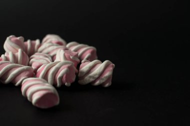 Marshmallow boşaltmak siyah zemin üzerine. Düz yatıyordu veya en iyi görünümü. Arka plan veya doku renkli mini lokum gibiydi.