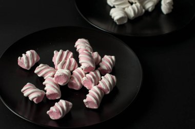 Marshmallow boşaltmak siyah zemin üzerine. Düz yatıyordu veya en iyi görünümü. Arka plan veya doku renkli mini lokum gibiydi.