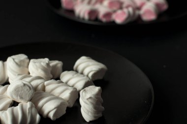 Marshmallow boşaltmak siyah zemin üzerine. Düz yatıyordu veya en iyi görünümü. Arka plan veya doku renkli mini lokum gibiydi.