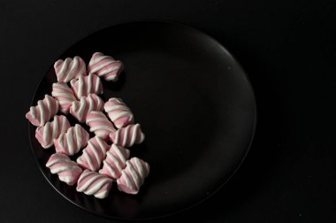 Marshmallow boşaltmak siyah zemin üzerine. Düz yatıyordu veya en iyi görünümü. Arka plan veya doku renkli mini lokum gibiydi.