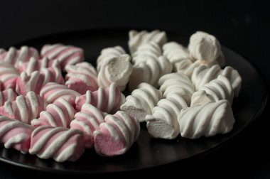 Marshmallow boşaltmak siyah zemin üzerine. Düz yatıyordu veya en iyi görünümü. Arka plan veya doku renkli mini lokum gibiydi.