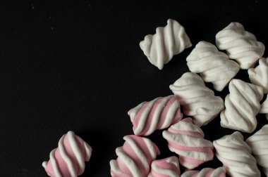 Marshmallow boşaltmak siyah zemin üzerine. Düz yatıyordu veya en iyi görünümü. Arka plan veya doku renkli mini lokum gibiydi.