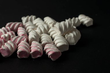 Marshmallow boşaltmak siyah zemin üzerine. Düz yatıyordu veya en iyi görünümü. Arka plan veya doku renkli mini lokum gibiydi.