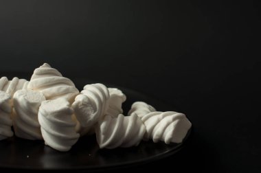 Marshmallow boşaltmak siyah zemin üzerine. Düz yatıyordu veya en iyi görünümü. Arka plan veya doku renkli mini lokum gibiydi.