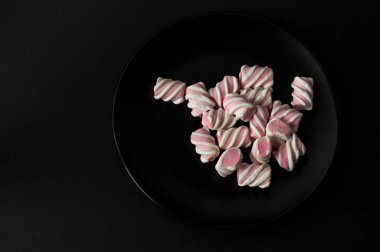 Marshmallow boşaltmak siyah zemin üzerine. Düz yatıyordu veya en iyi görünümü. Arka plan veya doku renkli mini lokum gibiydi.