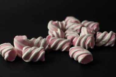 Marshmallow boşaltmak siyah zemin üzerine. Düz yatıyordu veya en iyi görünümü. Arka plan veya doku renkli mini lokum gibiydi.