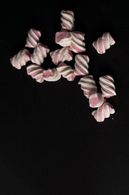 Marshmallow boşaltmak siyah zemin üzerine. Düz yatıyordu veya en iyi görünümü. Arka plan veya doku renkli mini lokum gibiydi.