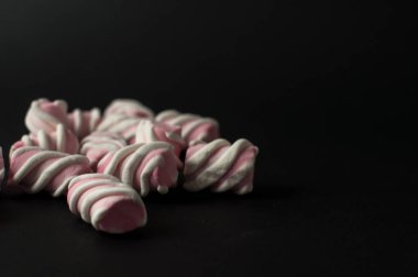 Marshmallow boşaltmak siyah zemin üzerine. Düz yatıyordu veya en iyi görünümü. Arka plan veya doku renkli mini lokum gibiydi.