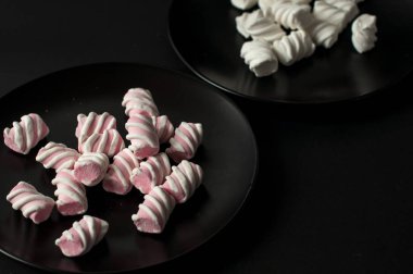 Marshmallow boşaltmak siyah zemin üzerine. Düz yatıyordu veya en iyi görünümü. Arka plan veya doku renkli mini lokum gibiydi.