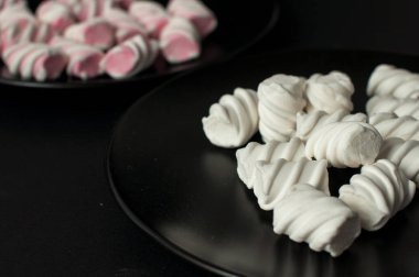 Marshmallow boşaltmak siyah zemin üzerine. Düz yatıyordu veya en iyi görünümü. Arka plan veya doku renkli mini lokum gibiydi.