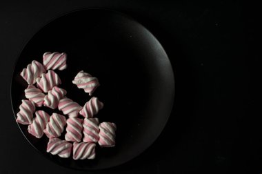 Marshmallow boşaltmak siyah zemin üzerine. Düz yatıyordu veya en iyi görünümü. Arka plan veya doku renkli mini lokum gibiydi.