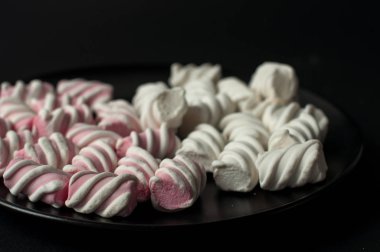 Marshmallow boşaltmak siyah zemin üzerine. Düz yatıyordu veya en iyi görünümü. Arka plan veya doku renkli mini lokum gibiydi.