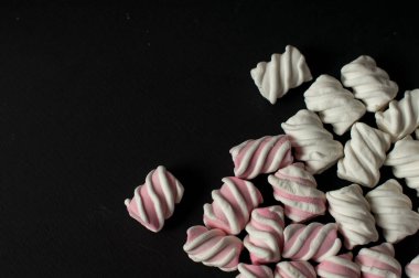Marshmallow boşaltmak siyah zemin üzerine. Düz yatıyordu veya en iyi görünümü. Arka plan veya doku renkli mini lokum gibiydi.