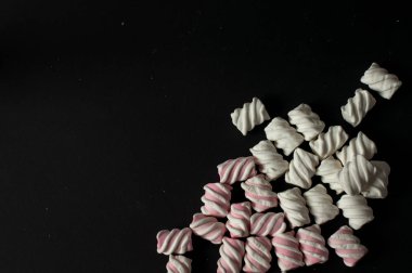 Marshmallow boşaltmak siyah zemin üzerine. Düz yatıyordu veya en iyi görünümü. Arka plan veya doku renkli mini lokum gibiydi.