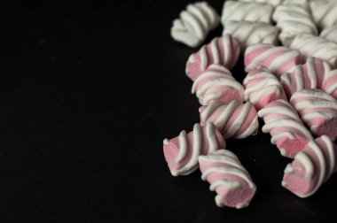 Marshmallow boşaltmak siyah zemin üzerine. Düz yatıyordu veya en iyi görünümü. Arka plan veya doku renkli mini lokum gibiydi.