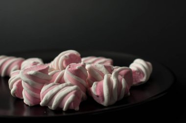 Marshmallow boşaltmak siyah zemin üzerine. Düz yatıyordu veya en iyi görünümü. Arka plan veya doku renkli mini lokum gibiydi.