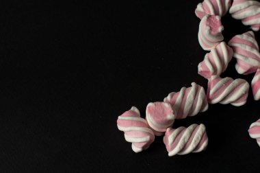 Marshmallow boşaltmak siyah zemin üzerine. Düz yatıyordu veya en iyi görünümü. Arka plan veya doku renkli mini lokum gibiydi.