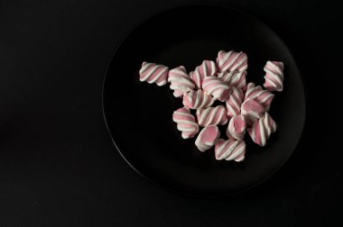 Marshmallow boşaltmak siyah zemin üzerine. Düz yatıyordu veya en iyi görünümü. Arka plan veya doku renkli mini lokum gibiydi.