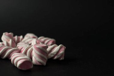 Marshmallow boşaltmak siyah zemin üzerine. Düz yatıyordu veya en iyi görünümü. Arka plan veya doku renkli mini lokum gibiydi.